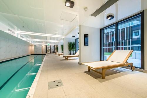 a swimming pool with benches in a building at Refreshing Central 2 Bedrooms on Queen St Living in Auckland