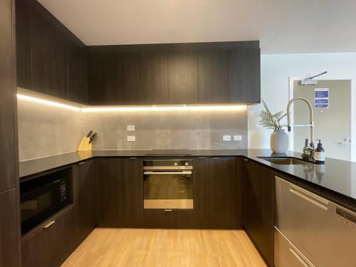 a kitchen with brown cabinets and a sink and a stove at Unique Luxury Incredible SkyTower & Park View - Free Parking in Auckland