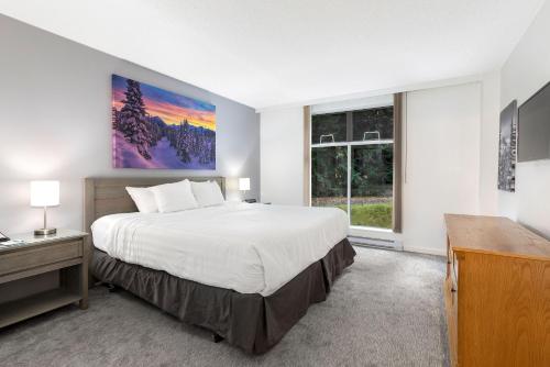 a bedroom with a large bed and a window at The Woodrun Lodge by Whiski Jack in Whistler