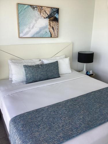 a bedroom with a large white bed with a picture on the wall at Rhapsody Resort - Official in Gold Coast