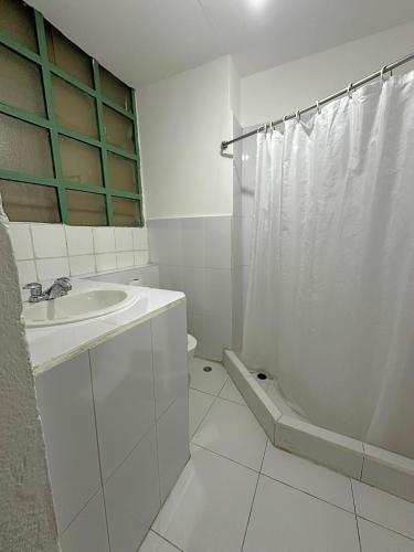 a white bathroom with a sink and a shower at Hostal Latina in Cuenca