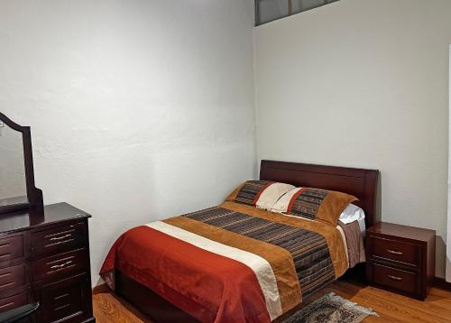 a small bedroom with a bed and a dresser at Hostal Latina in Cuenca