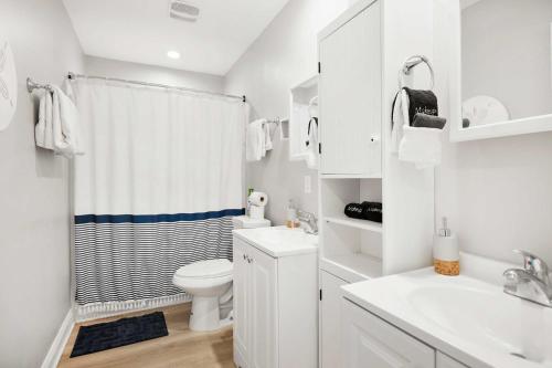 a white bathroom with a toilet and a sink at Secret Cottage 10 min to DT Dogs OK BBQ Parking in Saint Augustine