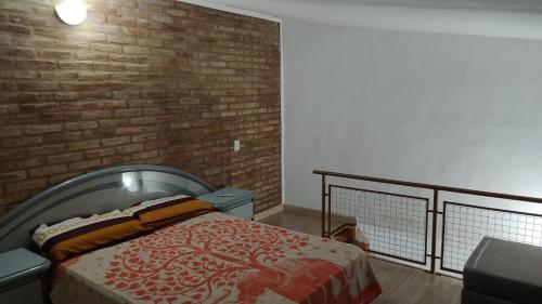 a bedroom with a bed and a brick wall at XayEm Apart in Villa Carlos Paz