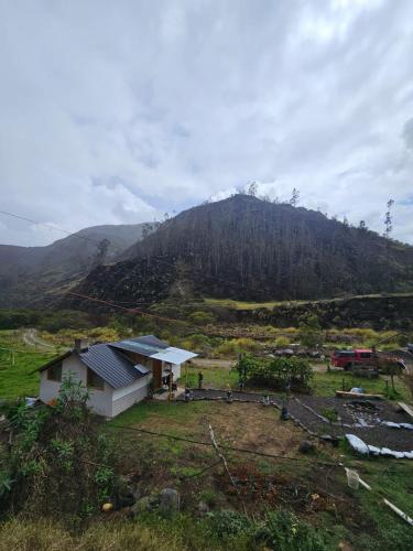a house in a field with a mountain in the background at The Frailejon Mountain in Sigchos