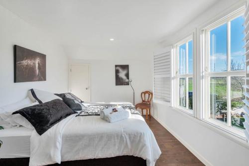 a white bedroom with a bed and windows at Nirvana Farm, Clevedon in Clevedon