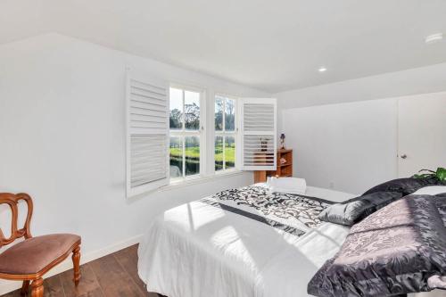 a white bedroom with a bed and a chair at Nirvana Farm, Clevedon in Clevedon