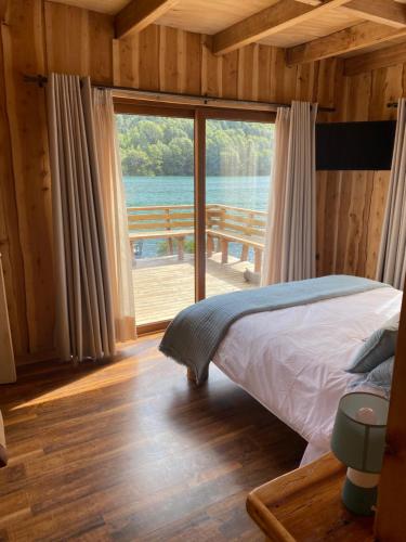 a bedroom with a bed and a large window at Refugio del Chucao in Llanada Grande