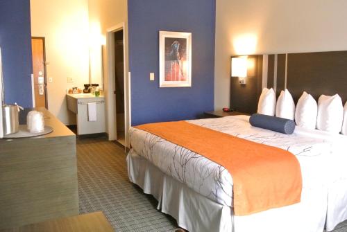 a hotel room with a large bed with an orange blanket at Guesthouse Inn & Suites Lexington in Lexington