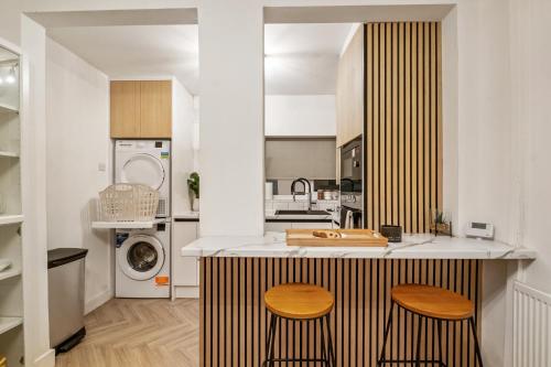 a kitchen with a counter with two stools at Luxury Cozy 2 bed house hot tub family friendly business traveler family of 4 - 6 with parking close to Birmingham city centre , M6 , Aston univerity , Great Barr Birmingham in Birmingham