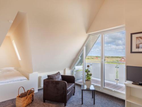 a living room with a chair and a large window at Dünenhuus Ost Modern retreat in Juist
