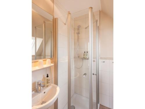 a white bathroom with a shower and a sink at Dünenhuus Ost Modern retreat in Juist