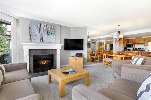 a living room with a fireplace and a tv at The Woodrun Lodge by Whiski Jack in Whistler