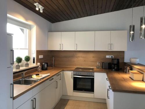 a kitchen with white cabinets and a sink and a window at Villa Alpenblick Comfortable holiday residence in Füssen
