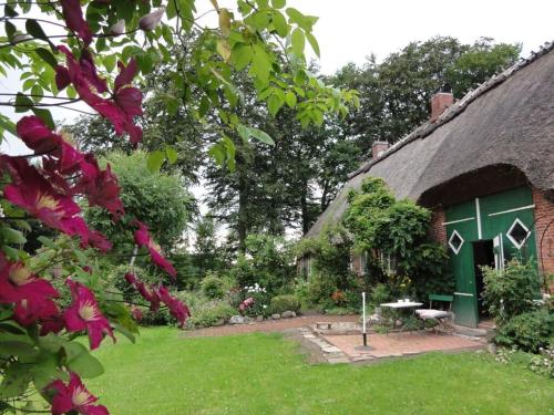 a house with a thatch roof with a garden at Romantic thatched roof house in Schnarup-Thumby