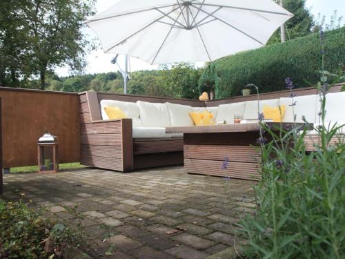 a patio with a white couch and an umbrella at Holiday home chalet on the castle hill in Brotterode-Trusetal