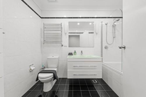 a white bathroom with a toilet and a shower at Comforting 2BR House & FishMarket & Casino-3 mins walk in Sydney