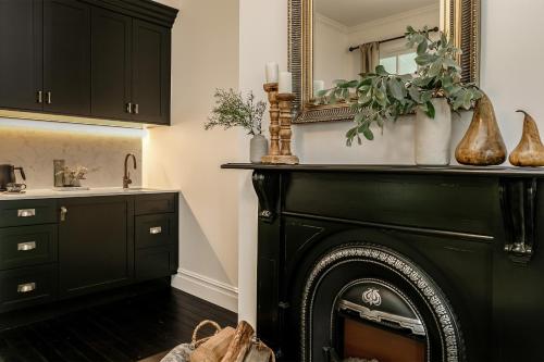 a black fireplace in a kitchen with a mirror at Narraweema Guesthouse - Historic Luxury BnB Retreat in Gloucester