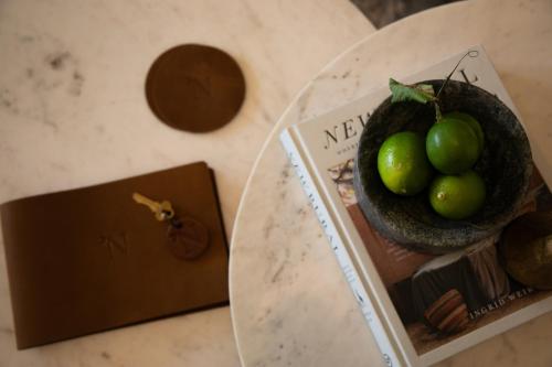 a person holding a bowl of green fruit on a table at Narraweema Guesthouse - Historic Luxury BnB Retreat in Gloucester