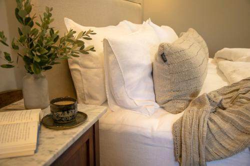 a bed with white pillows and a vase with a book at Narraweema Guesthouse - Historic Luxury BnB Retreat in Gloucester
