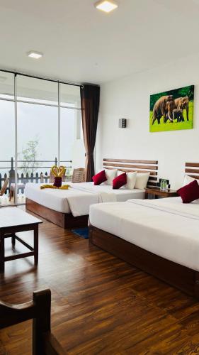 a bedroom with three beds and a large window at Mountain Paradise Bliss Guest House in Haputale