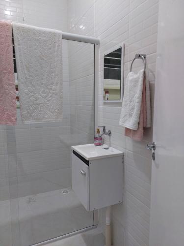 a white bathroom with a sink and a shower at Porto Belo Perequê in Porto Belo