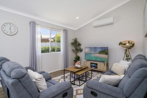 a living room with two blue chairs and a tv at Bright and Spacious 2-Bed Thornlie Family Home in Perth