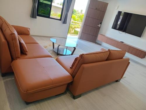 a living room with two brown couches and a table at Hibiscus Suites And Residences in Nadi