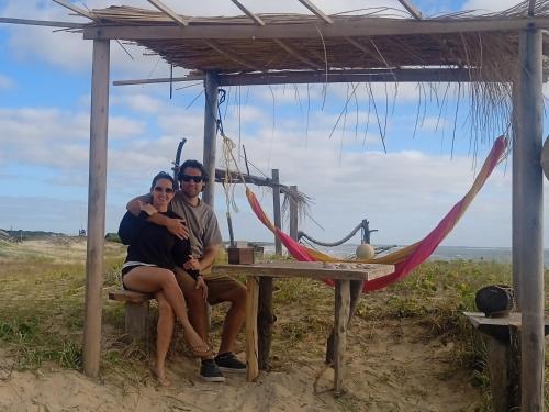 a man and woman sitting at a picnic table at the beach at Para un poquito relax in Barra de Valizas