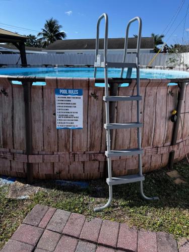 a ladder next to a swimming pool with a sign at Palm Beach Paradise in West Palm Beach