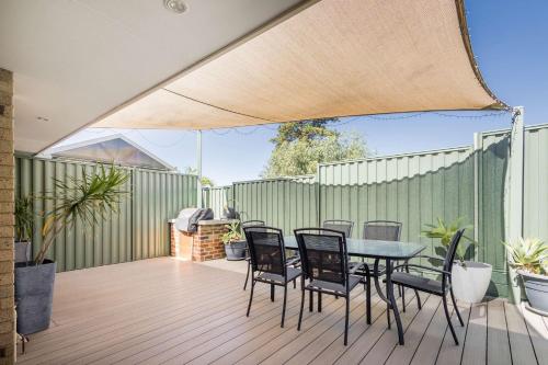 a patio with a table and chairs on a deck at Sunset Villa Scarborough in Perth