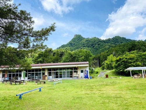 a building in a field with a mountain in the background at Heguri Hub in Minamiboso