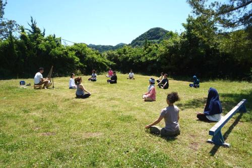 a group of people sitting in the grass at Heguri Hub in Minamiboso