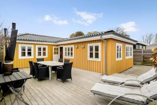 a yellow house with a table and chairs on a deck at Nordenhus in Nyborg