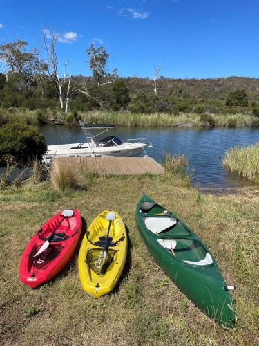 three kayaks sitting on the grass next to a river at Swan River Sanctuary in Swansea