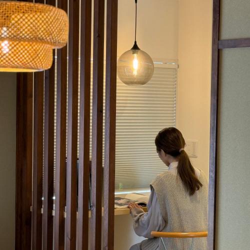 a woman sitting in a chair looking at her cell phone at Shiki Villa Beppu in Beppu