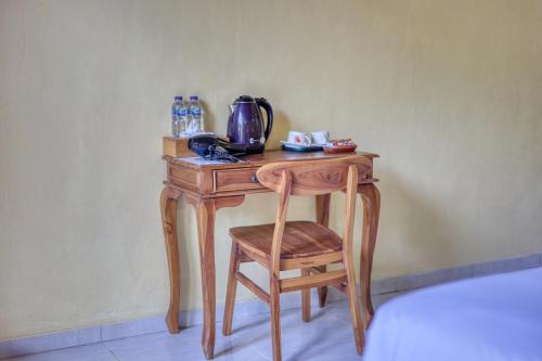 un tavolo in legno con sedia e un bollitore per il tè. di Maharga Bungalows a Nusa Penida