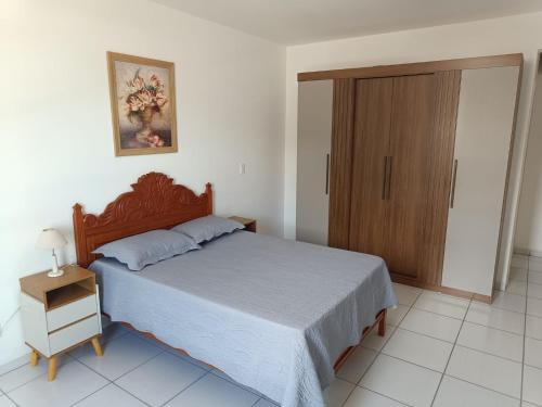 a bedroom with a bed and a wooden cabinet at Apartamento no Mar Grosso em Laguna SC. in Laguna