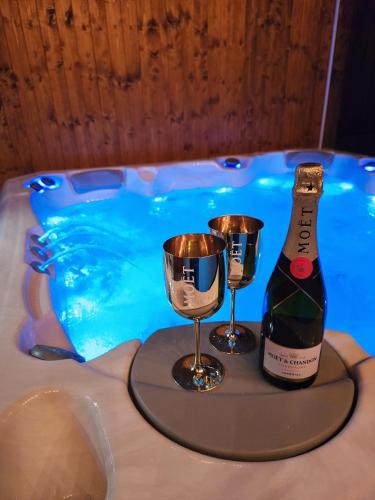 a bottle of champagne and two glasses on a table next to a swimming pool at Vila MAX - WHIRLPOOL & BAZÉN & SAUNA in Velké Losiny