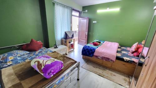 two beds in a room with green walls at Seven Hills Homestay in Kalimpong