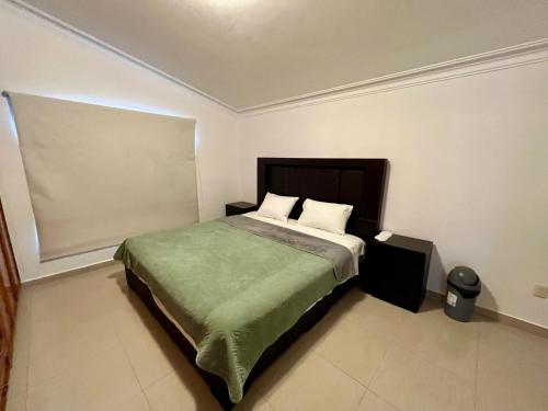 a bedroom with a large bed with a green blanket at 21 Habitación cama king size in Miravalle