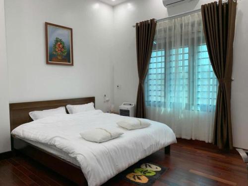 ein Schlafzimmer mit einem großen weißen Bett mit einem Fenster in der Unterkunft Rose Villa Thai Nguyen - Venuestay in Thượng Nhân