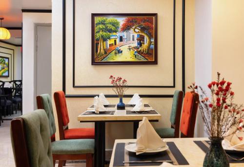 a dining room with a table and chairs and a painting at Hanoi Calista Hotel & Spa in Hanoi