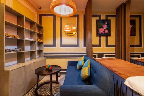 a bedroom with a blue couch and a table at Hanoi Calista Hotel & Spa in Hanoi