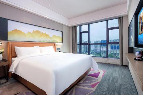 a bedroom with a large white bed and large windows at Hampton by Hilton Zhangjiajie Tianmen Mountain in Zhangjiajie
