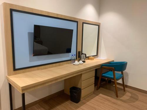 a room with a desk with a television and a chair at Nite & Day Laguna Bintan in Tanjung Pinang 