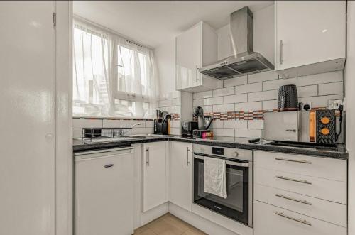 a white kitchen with white appliances and a window at Amazing Marina-Overlooking 1Bed in London