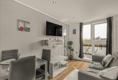 a white living room with a couch and a tv at Amazing Marina-Overlooking 1Bed in London