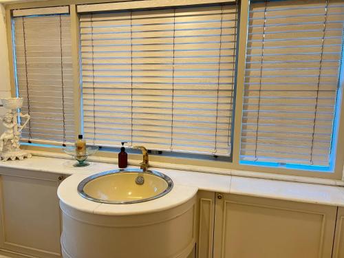 a bathroom with a sink and a window with blinds at V20 Boutique Jacuzzi Hotel in Bangkok