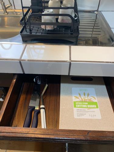 a drawer in a shelf with some kitchen utensils at Hospedaje Oropendola Nest in Bagaces